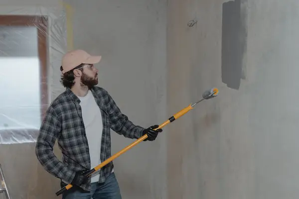 Painter rolling grey paint onto an interior wall in Wilmington